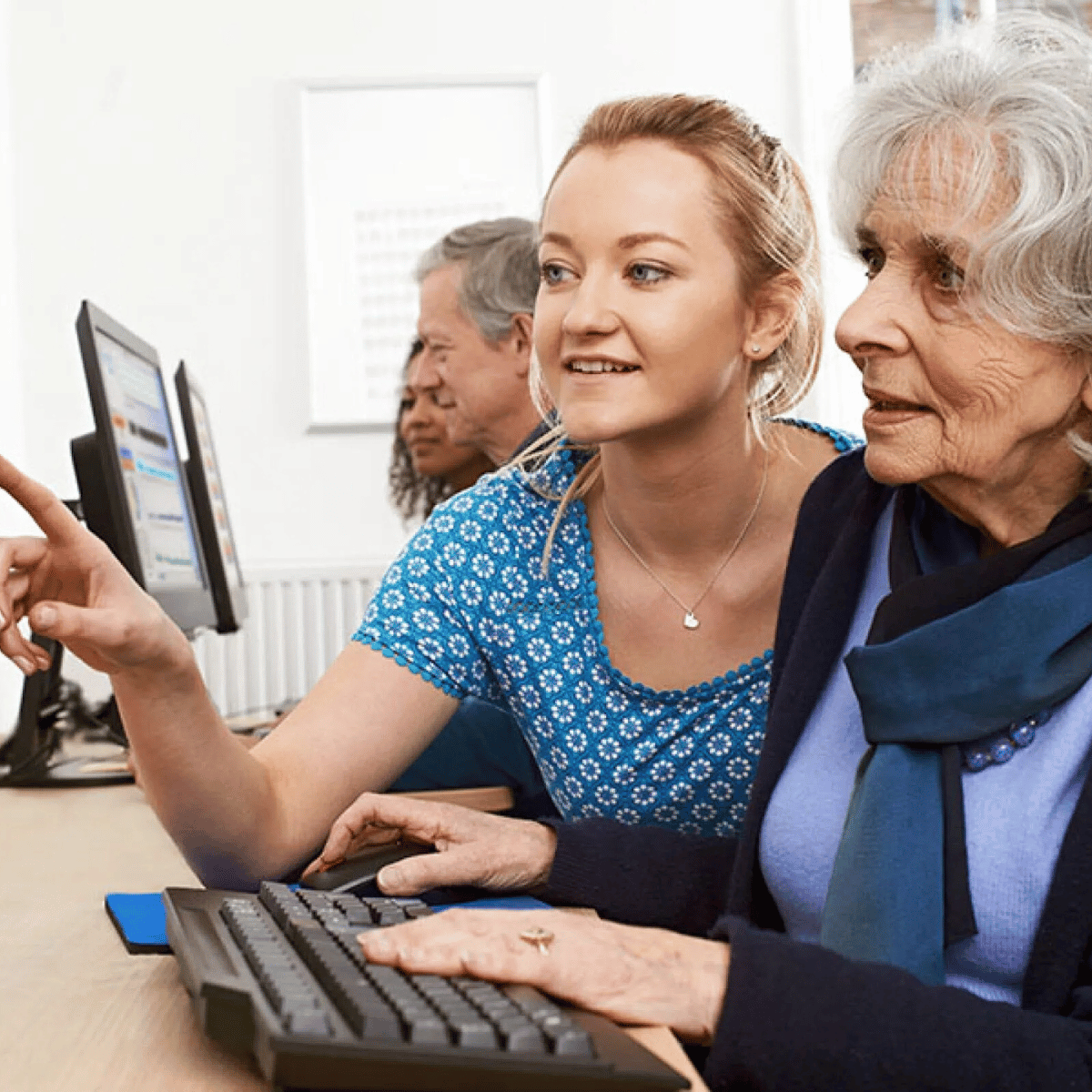 Instructora ayudando a una alumna con computadora